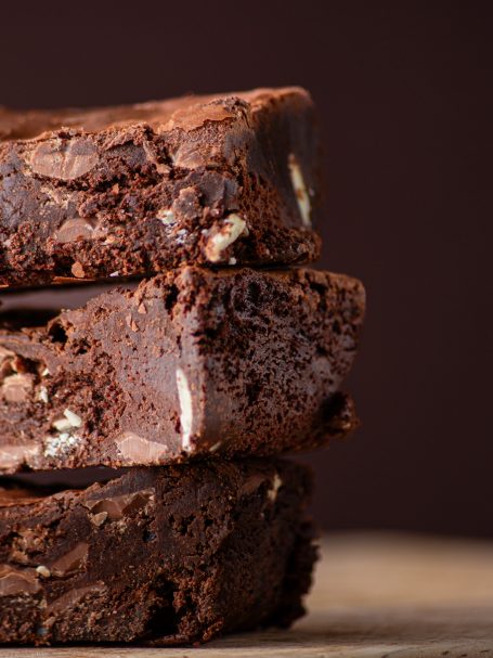 Three chocolate brownies stacked on top of each other, showcasing a rich, fudgy texture.